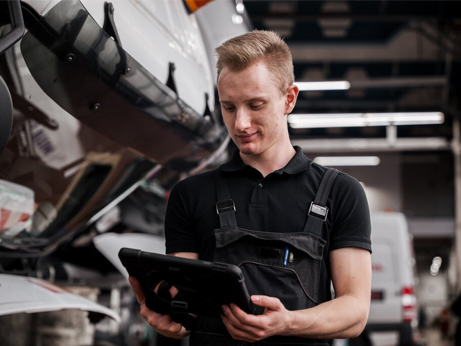 Mechaniker schaut auf Tablet mit Prüf-Protokoll