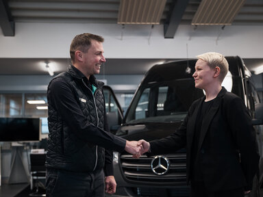 Handschlag zwischen Serviceberater und Kundin vor Mercedes-Benz Transporter