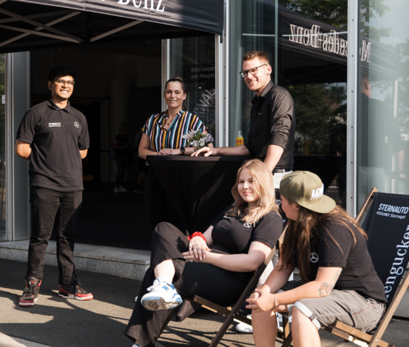 Ausbilder und Auszubildende vor Messestand